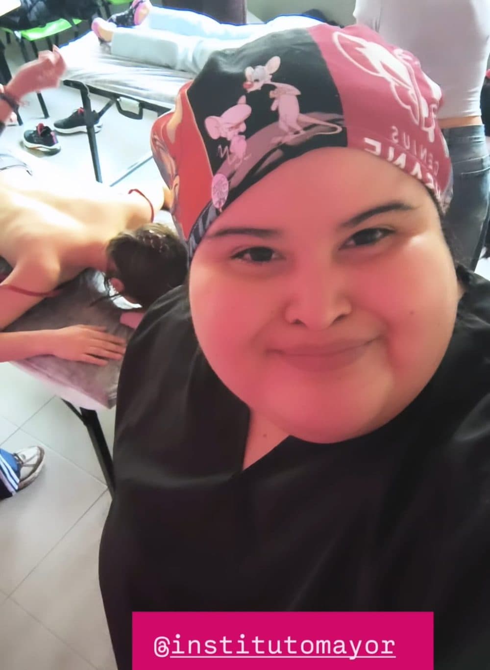 Yanina Deplante con ambo de trabajo en el aula del Instituto Mayor, durante una práctica de masaje sobre camillas.